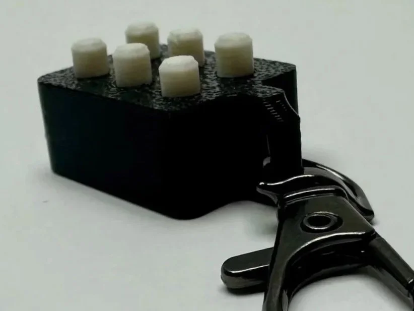Close-up of braille cell fidget, with all 6 white pegs up.