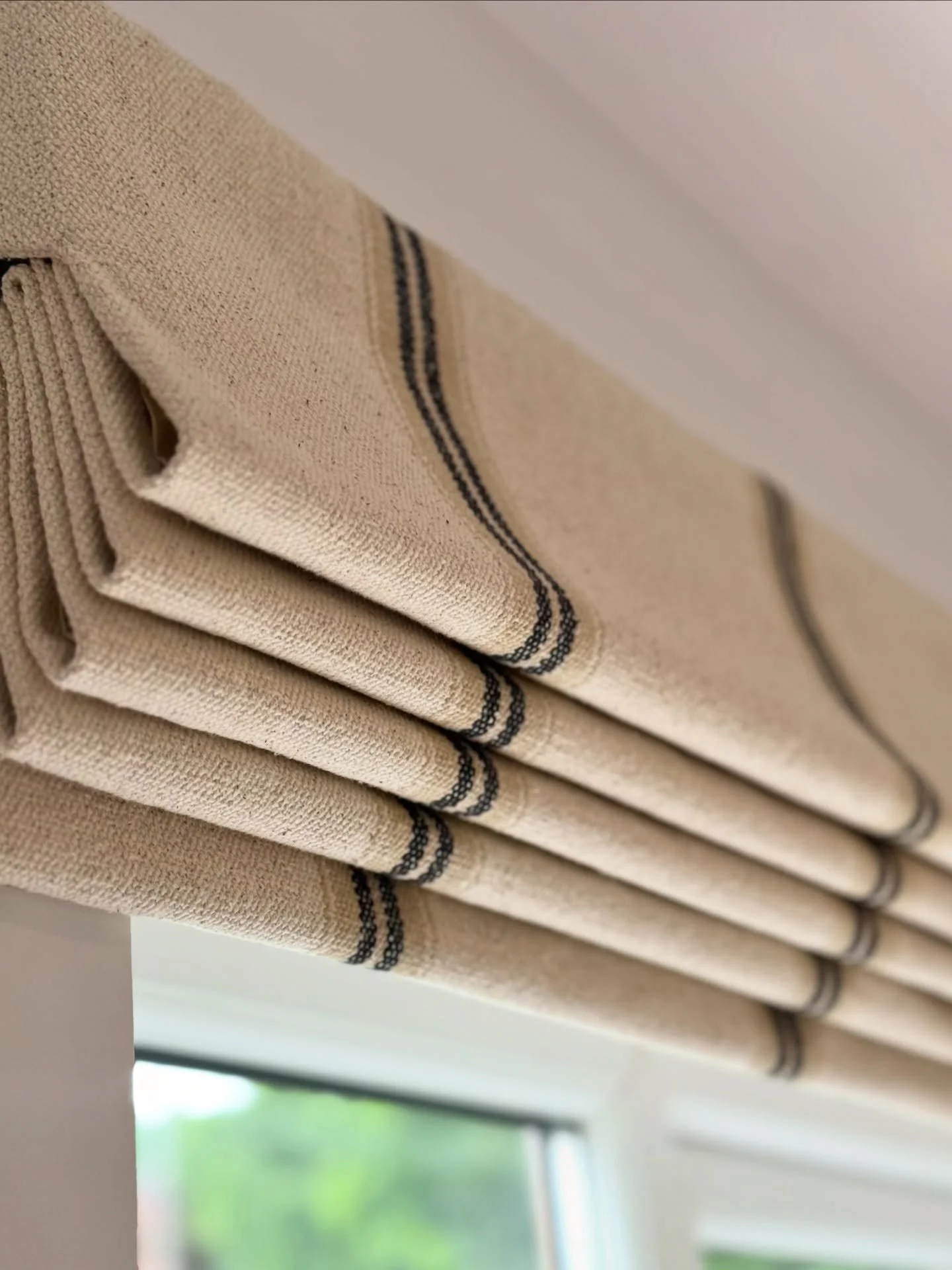 A gorgeous pair of hand lined, rustic Roman blinds for our client&rsquo;s contemporary kitchen. The natural feel of the grain sack fabric brings essential warmth and texture to the space; and looks stunning made up by our talented head seamstress Deb