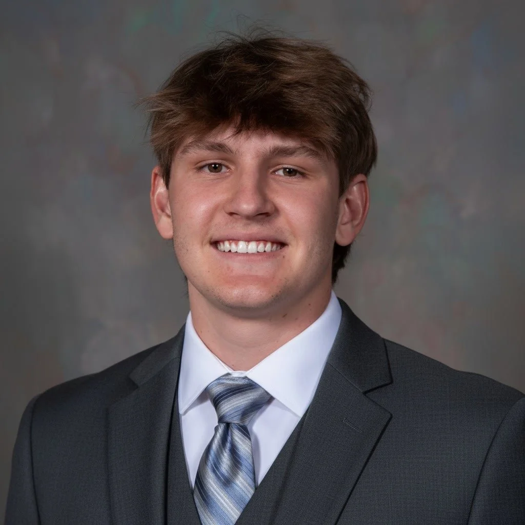 Dylan Cleveland Headshot in black suit on grey background