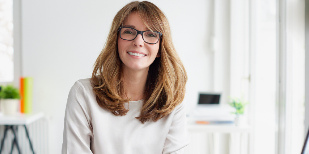 Smiling woman at work in a supportive, menopause-inclusive workplace promoting employee wellbeing and retention