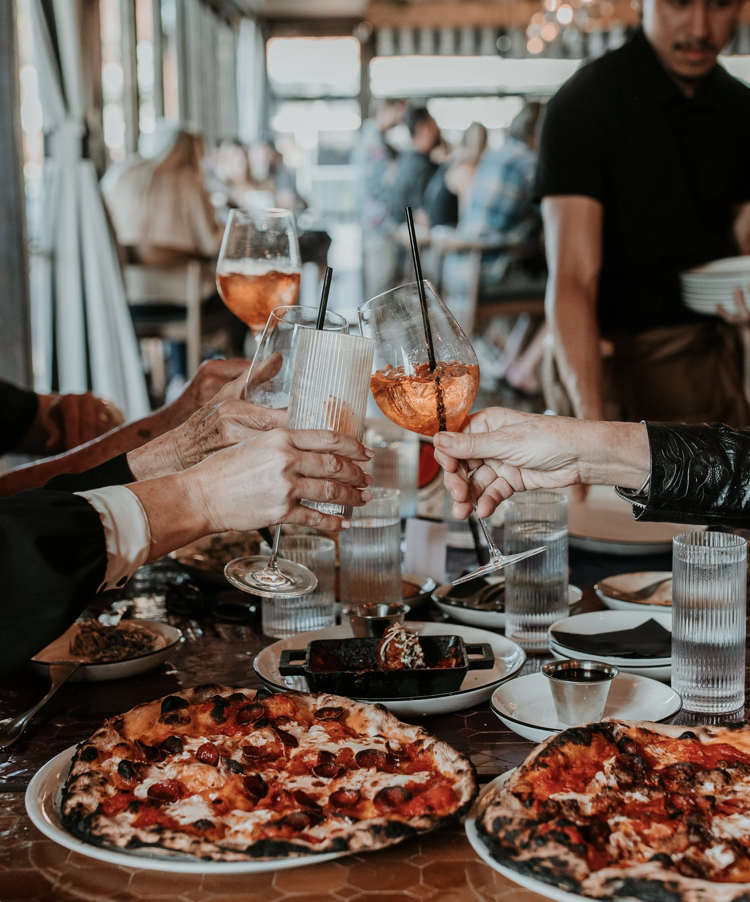 People cheersiing their drinks and enjoying happy hour at Pizza To The Rescue