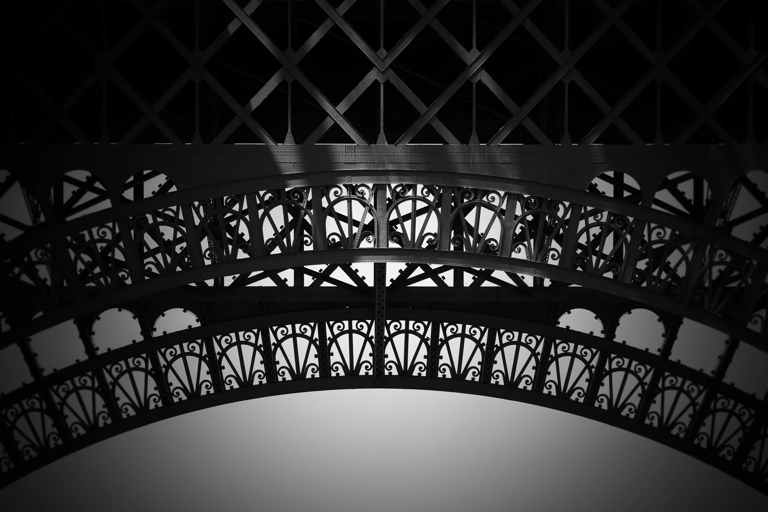 Close-up of the Eiffel Tower's intricate ironwork in black and white.