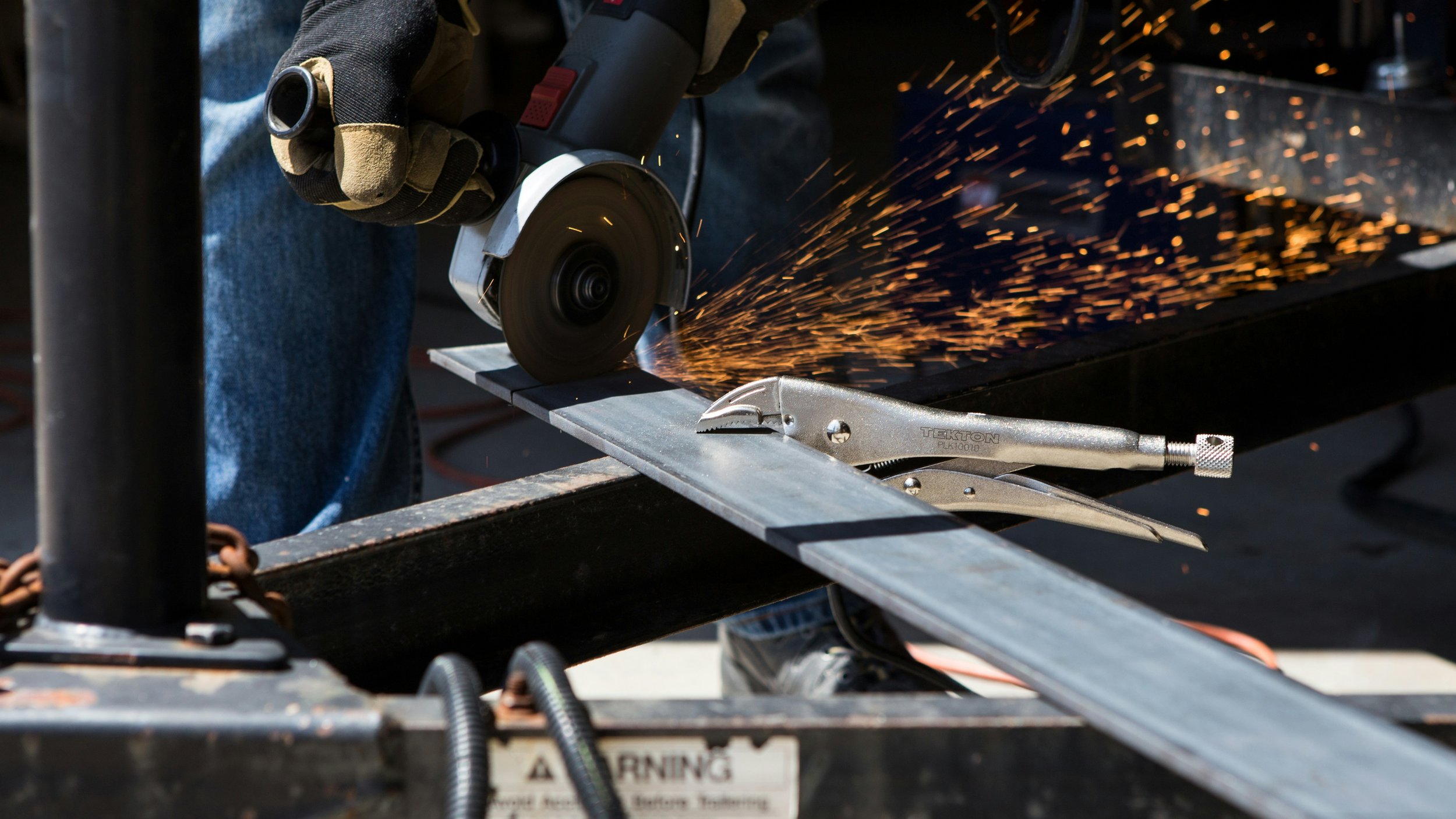 A person cutting metal with a handheld circular saw, sparks flying as the blade contacts the metal.