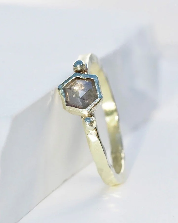 A Misfit salt and pepper diamond, recycled gold, organic hexagon bezel, gold beads and a hand-shaped band give this ring instant appeal. And one of the best things is that no two can ever be exactly alike. 

This sort-of perfectly-imperfect metalwork