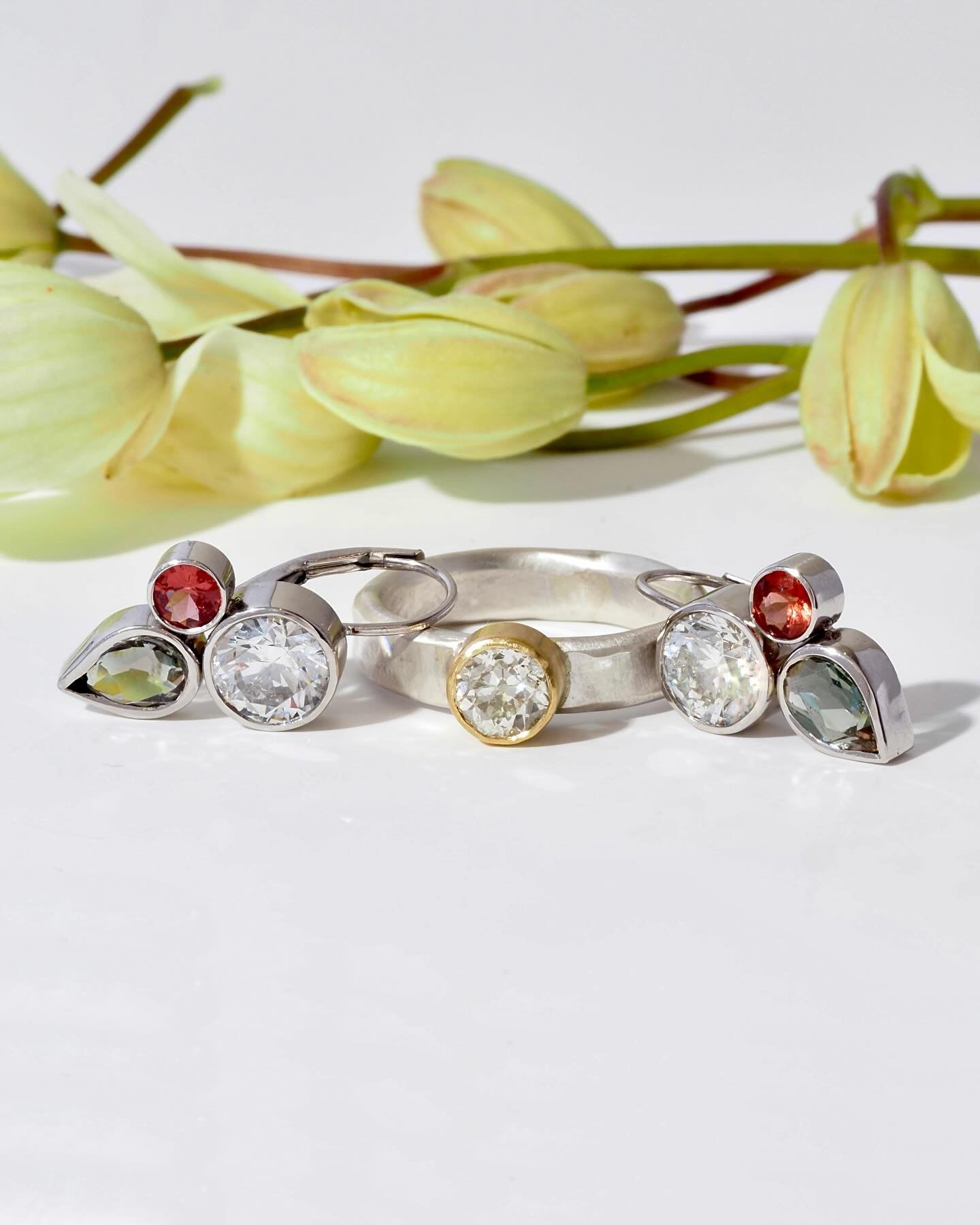 Custom earring and ring set. Made using a mix of the customer&rsquo;s and Fancy&rsquo;s gems. Recycled white gold with a yellow gold bezel on the diamond solitaire ring. Clematis blossoms in the background&hellip; they&rsquo;re just now starting to b