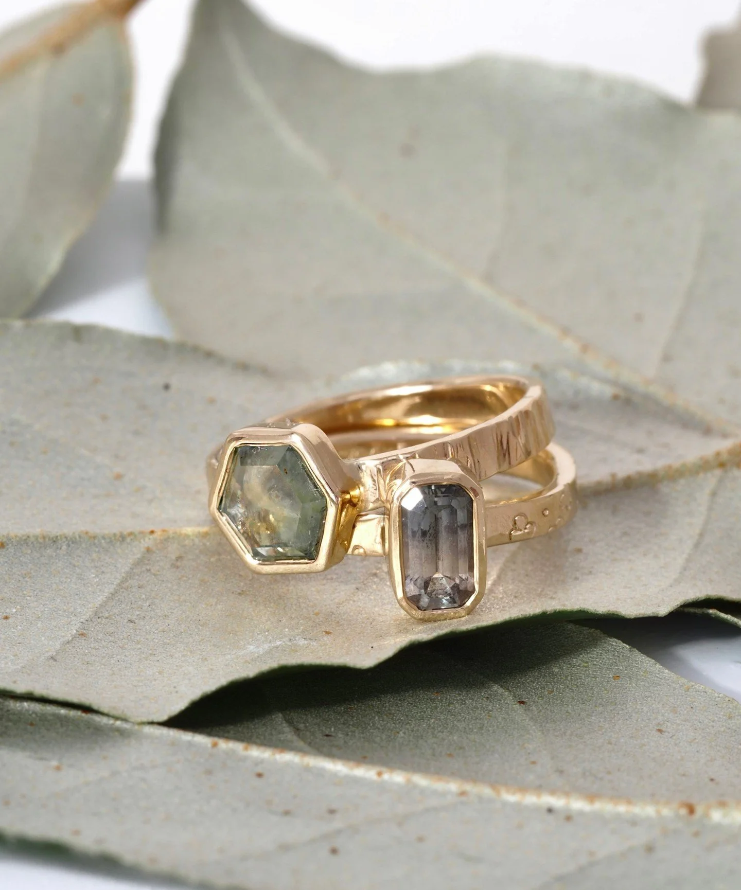 Gorgeous green/gray sapphire rings. The sapphires are ethically mined in Montana! Take note of the texture on the bands. One is hand sculpted in an organic texture inspired by the striped bark on maple trees and the other band has tiny flowers carved