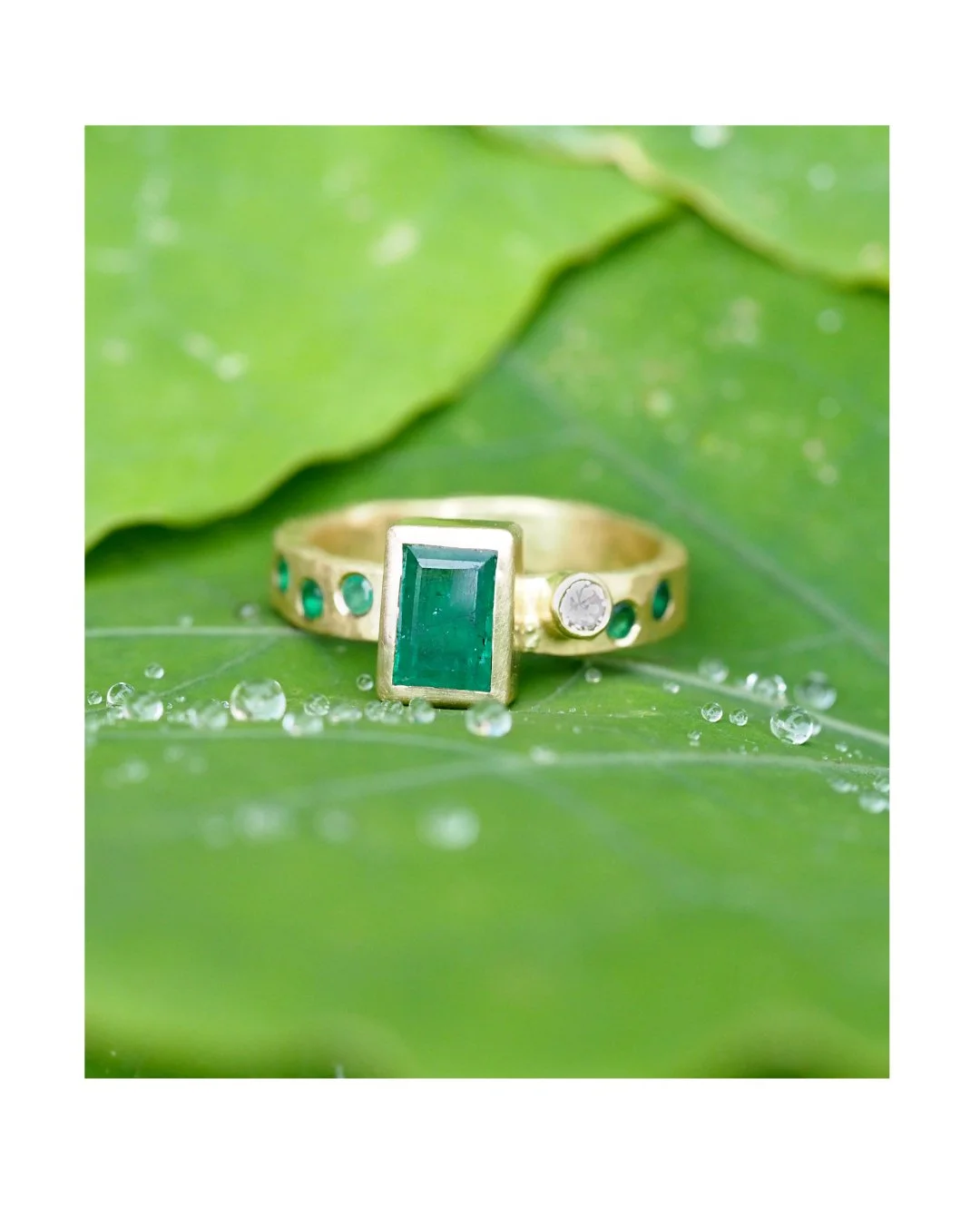 Good morning Fancy friends! This is a custom ring... an emerald cut emerald with dapples of emeralds in the band and accented with an offset diamond. 18K recycled gold shaped into a hand-textured band for extra character.

In case you are wondering, 