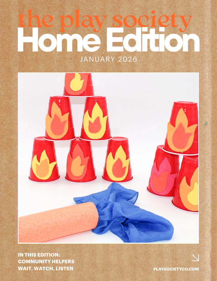 Cover of The Play Society Home Edition January 2026 featuring a stack of red cups with flame stickers, a rolled orange object, and a blue cloth.