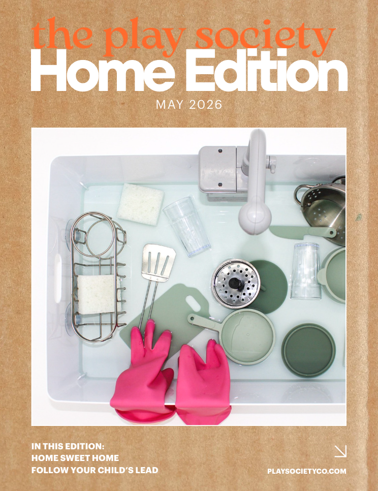 Magazine cover titled 'the play society Home Edition' for May 2026, featuring a top-down view of a kitchen sink with pink rubber gloves, cleaning tools, and containers.
