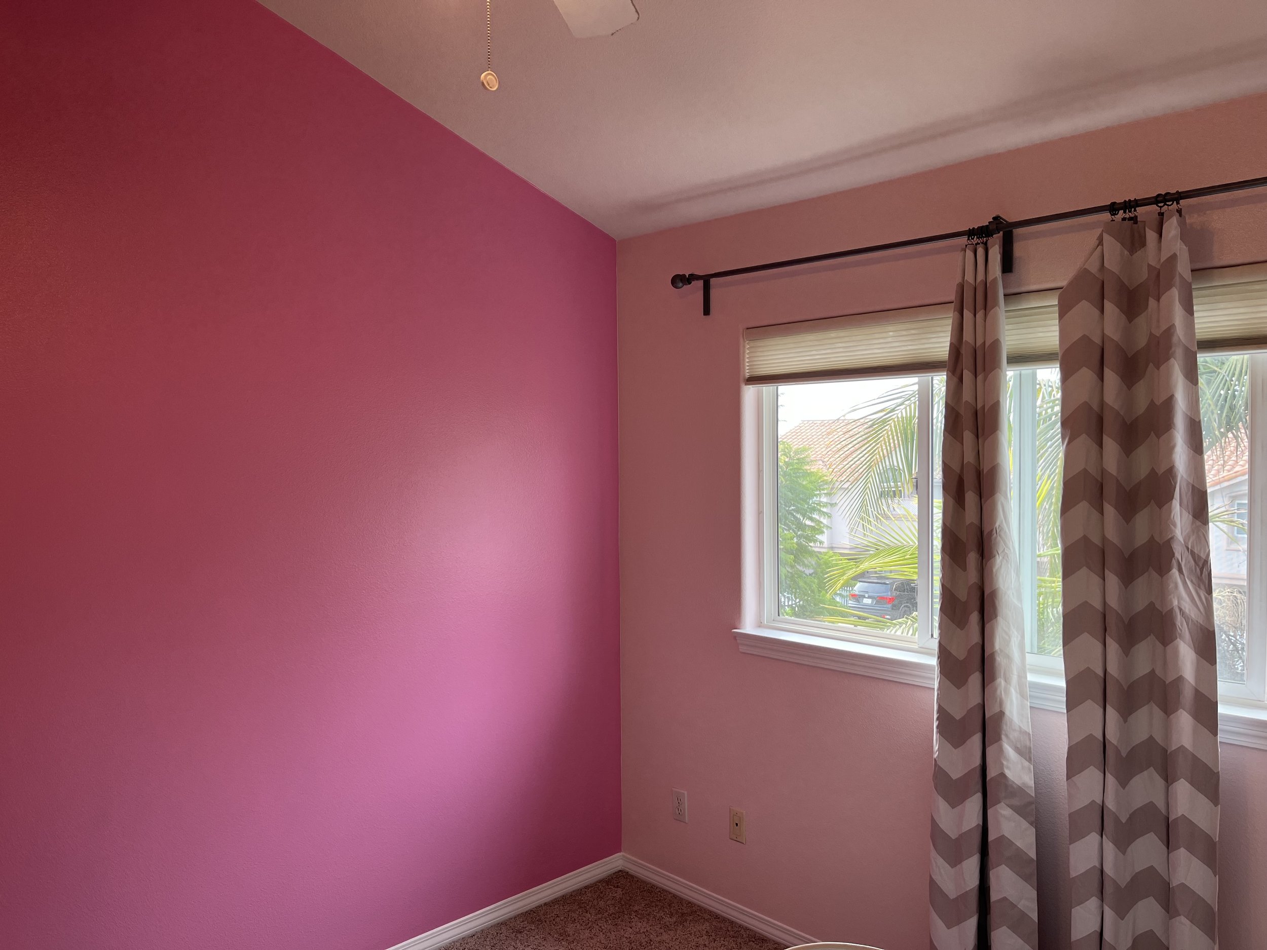 Living room with a large glass sliding door leading to a balcony with outdoor furniture, overlooking a cityscape and water in the distance.