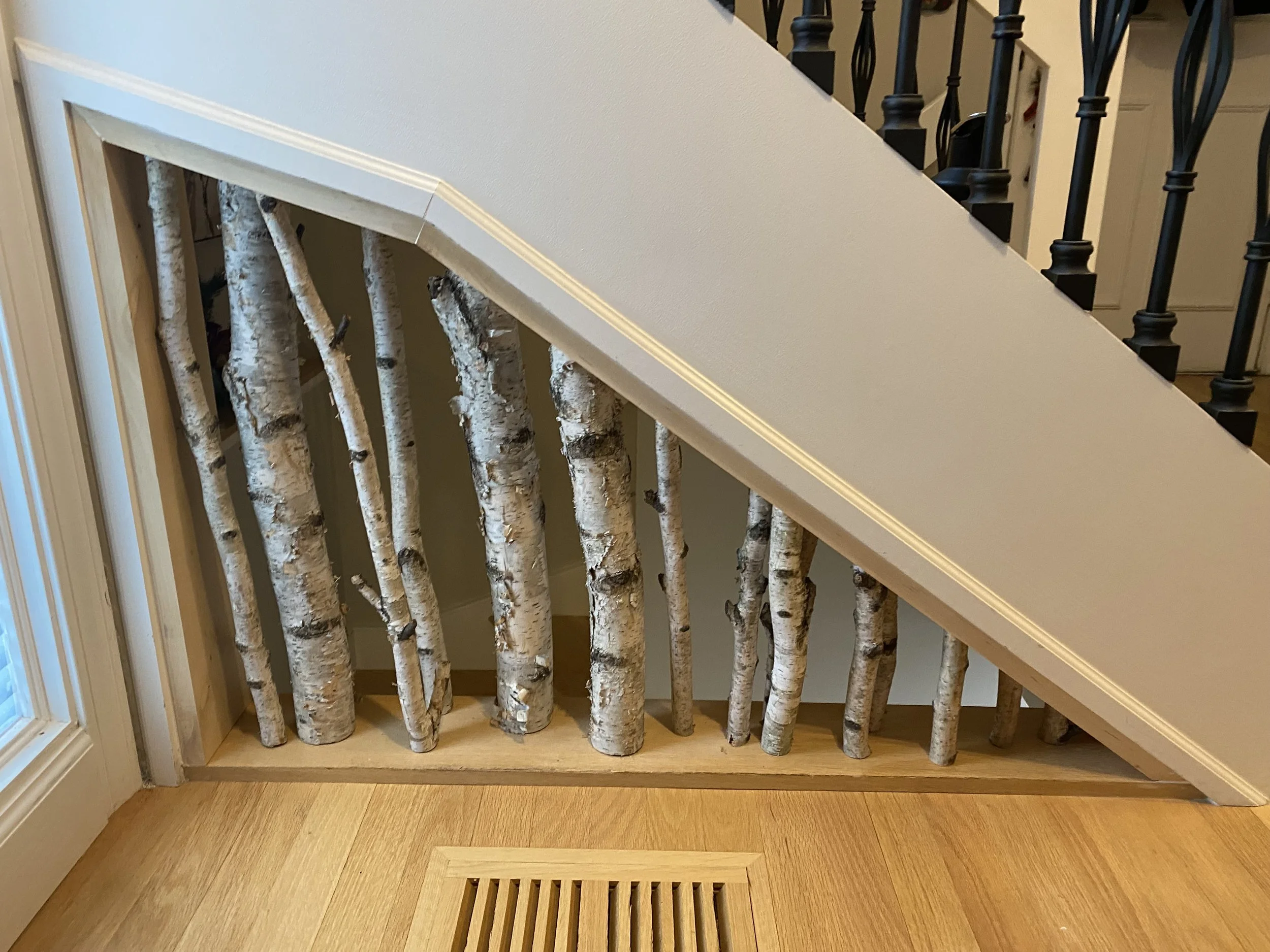 Wooden staircase with birch logs as balusters and a beige wall with crown molding.