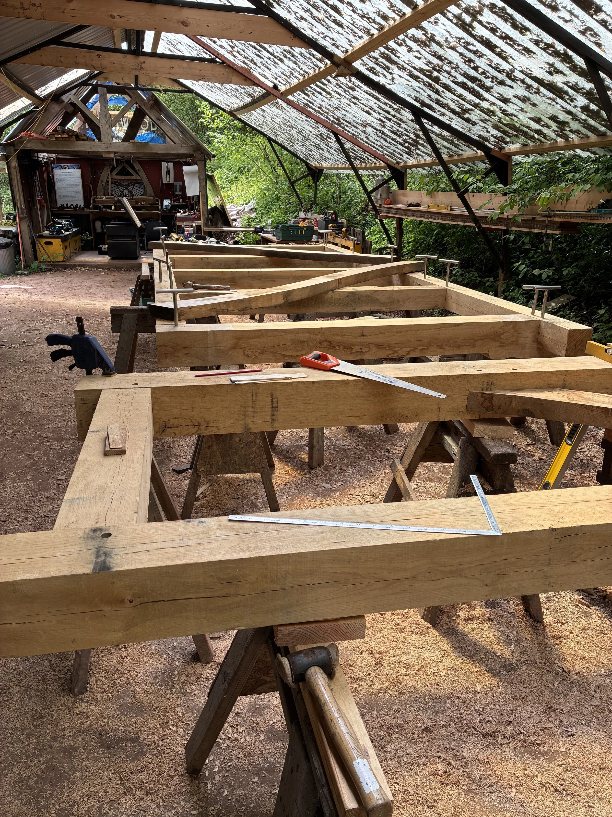 Wooden framework being assembled in a workshop with tools and measurements.