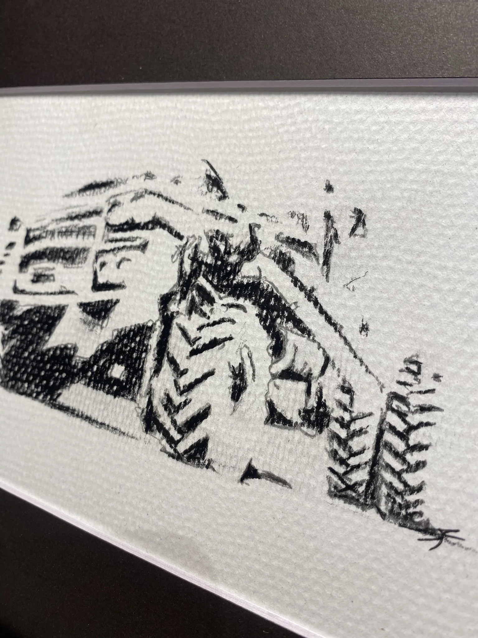 Close-up of a black and white ink drawing of a fish, possibly a koi, above water with detailed scales and fins, on a textured white paper surface.