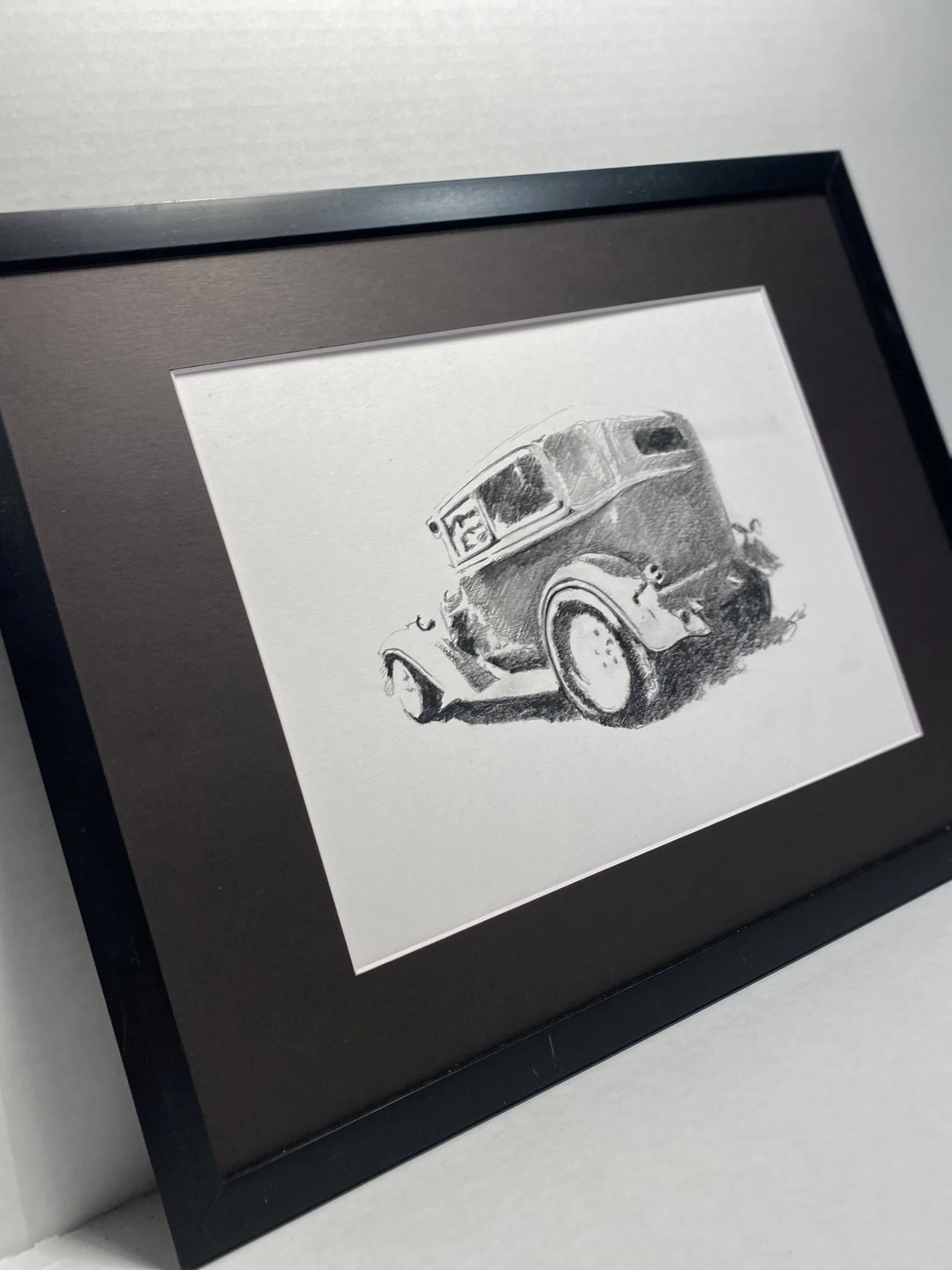 Black picture frame containing a sketch of a vintage pickup truck, displayed against a white background.