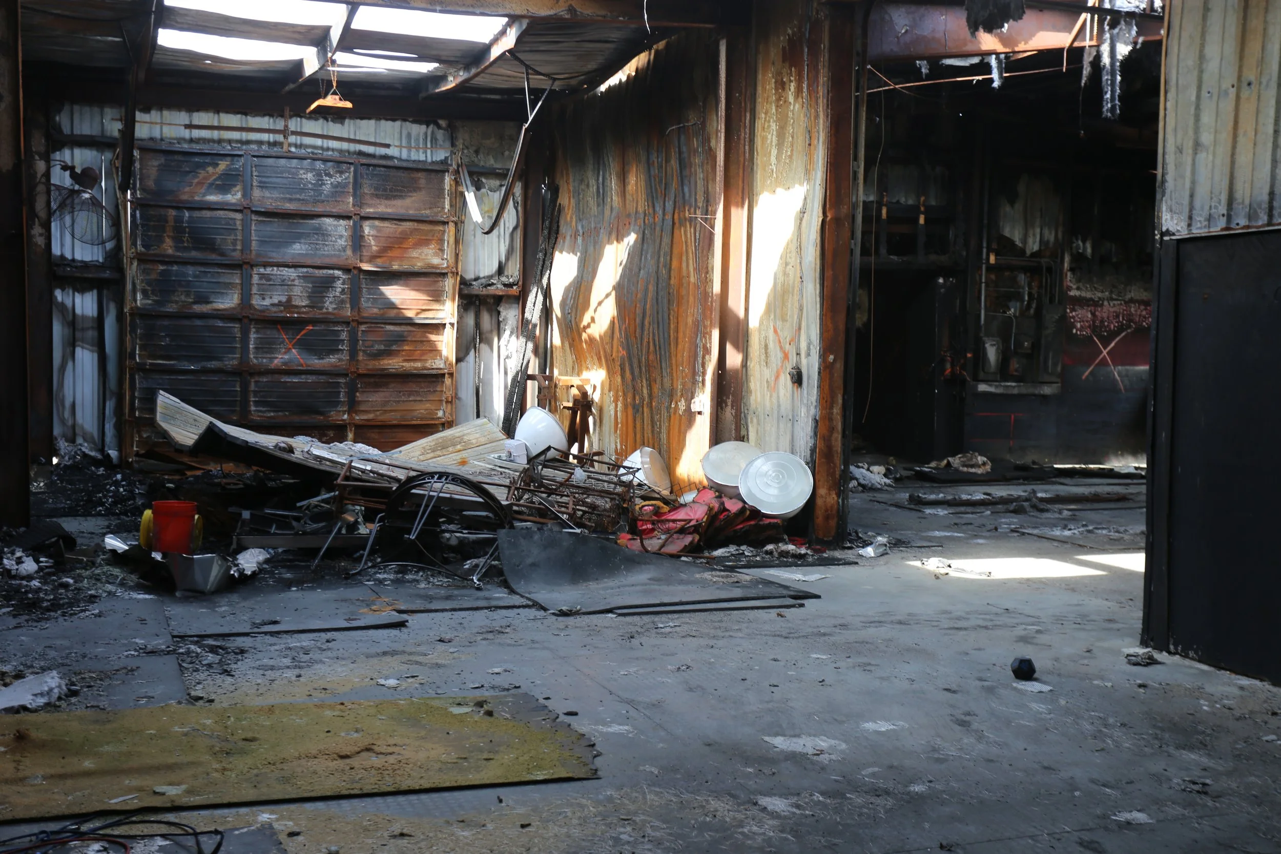 Fire-damaged room with burnt walls, debris, and melted items after a fire