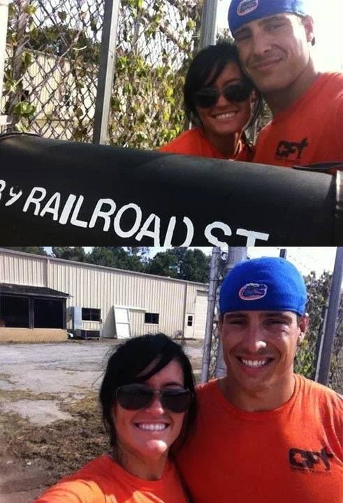 Two people, a woman with dark hair and sunglasses and a man with short hair wearing a blue cap and orange shirt, posing for selfies in front of a chain-link fence and a building. The woman in the first photo is smiling, and the man in the second phot