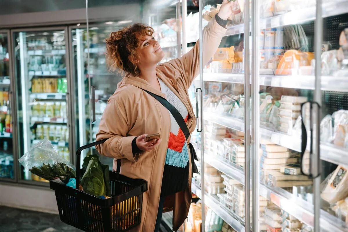 woman shopping in freezer aisle for groceries
