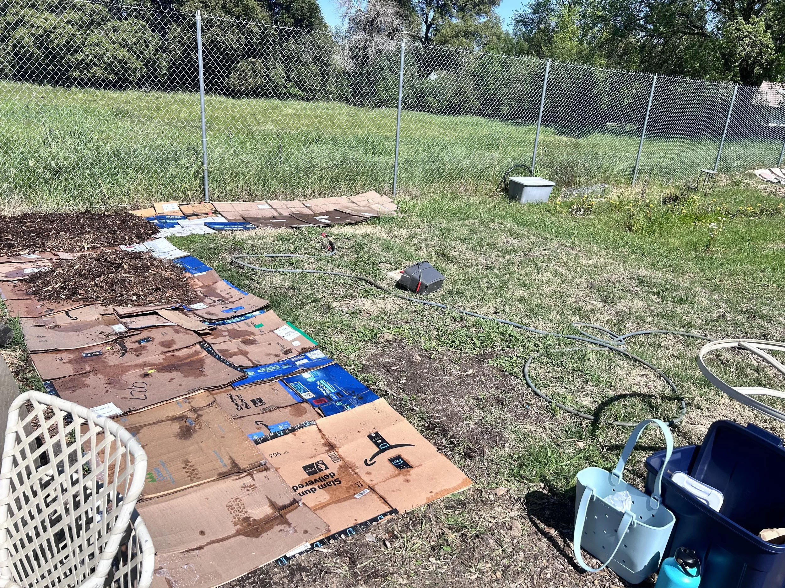 Sheet mulching and watering process at Amari Home Health and Hospice community garden to prepare soil for planting.