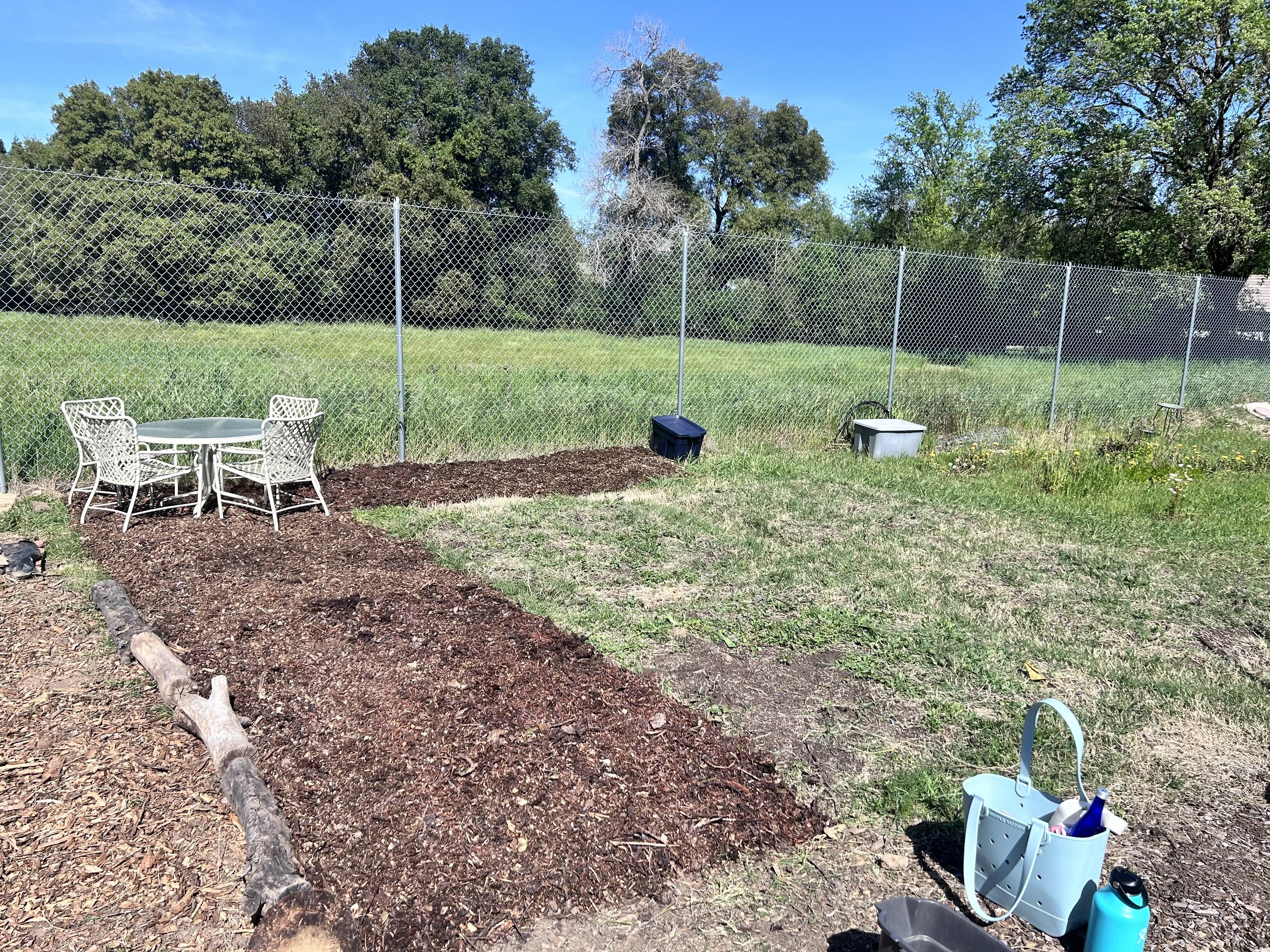Mulched garden beds and seating area at Amari Home Health and Hospice community garden during early development.