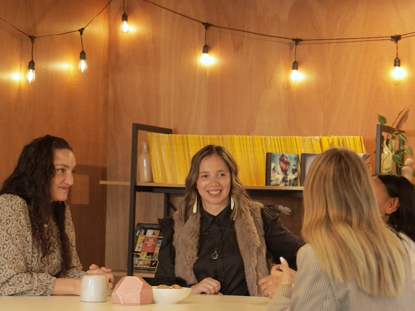 A group of four women at a table, Amy McLean facilitating a conversation