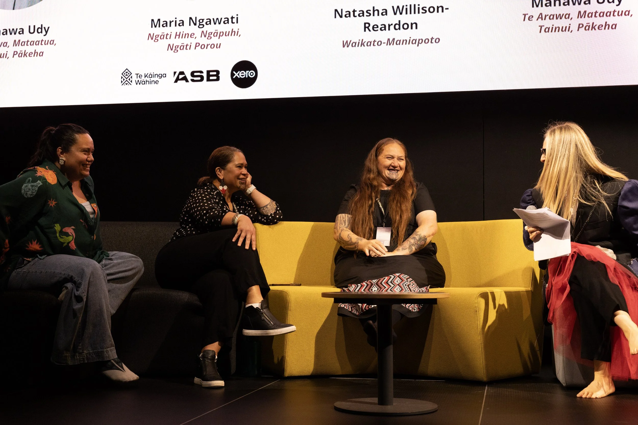 Te Mana o Ngā Wāhine Panel Speakers sitting on a grey and yellow couch