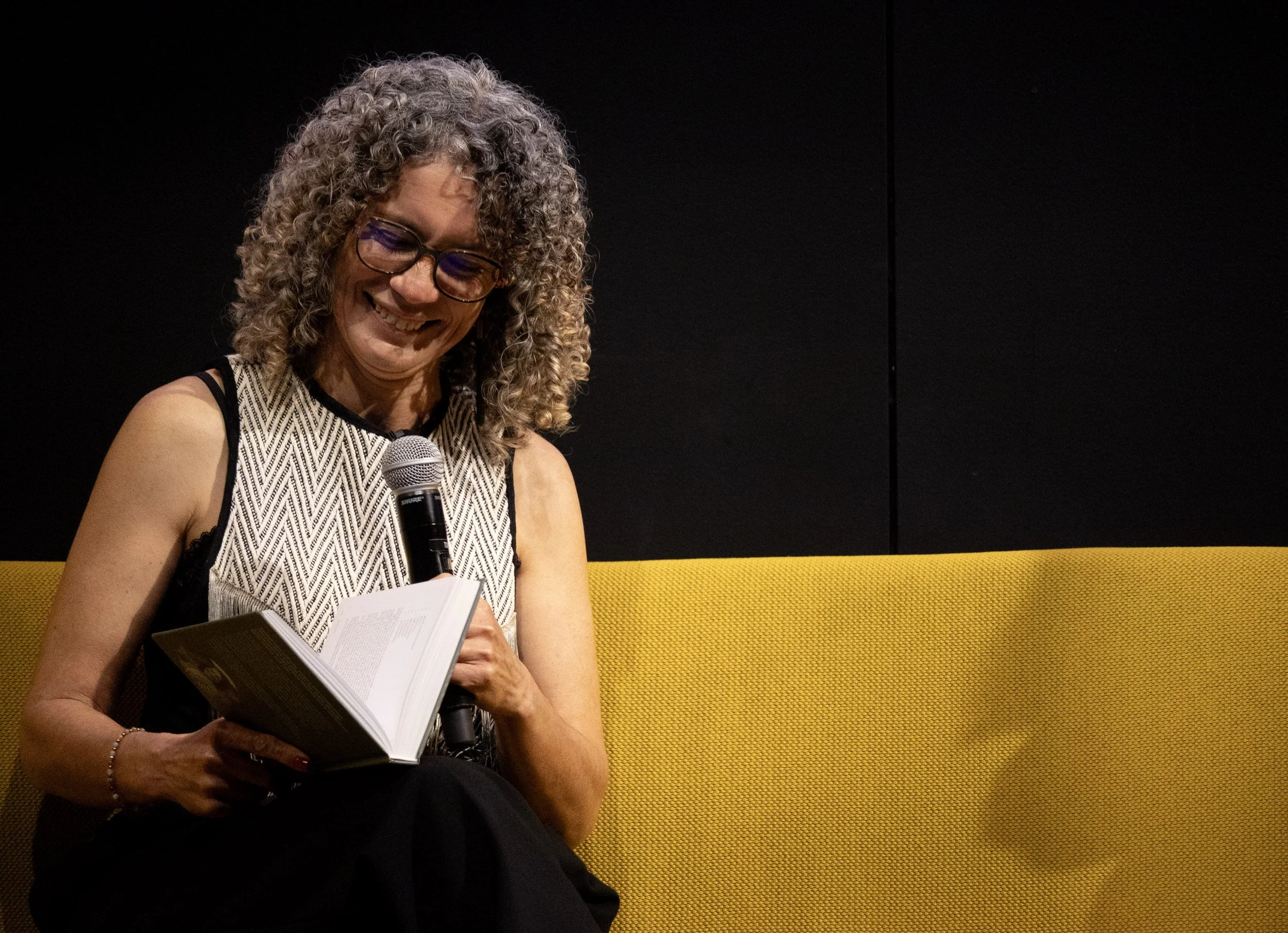Tracy Manu sitting on stage at Te Mana o Ngā Wāhine reading from her pukapuka Hononga