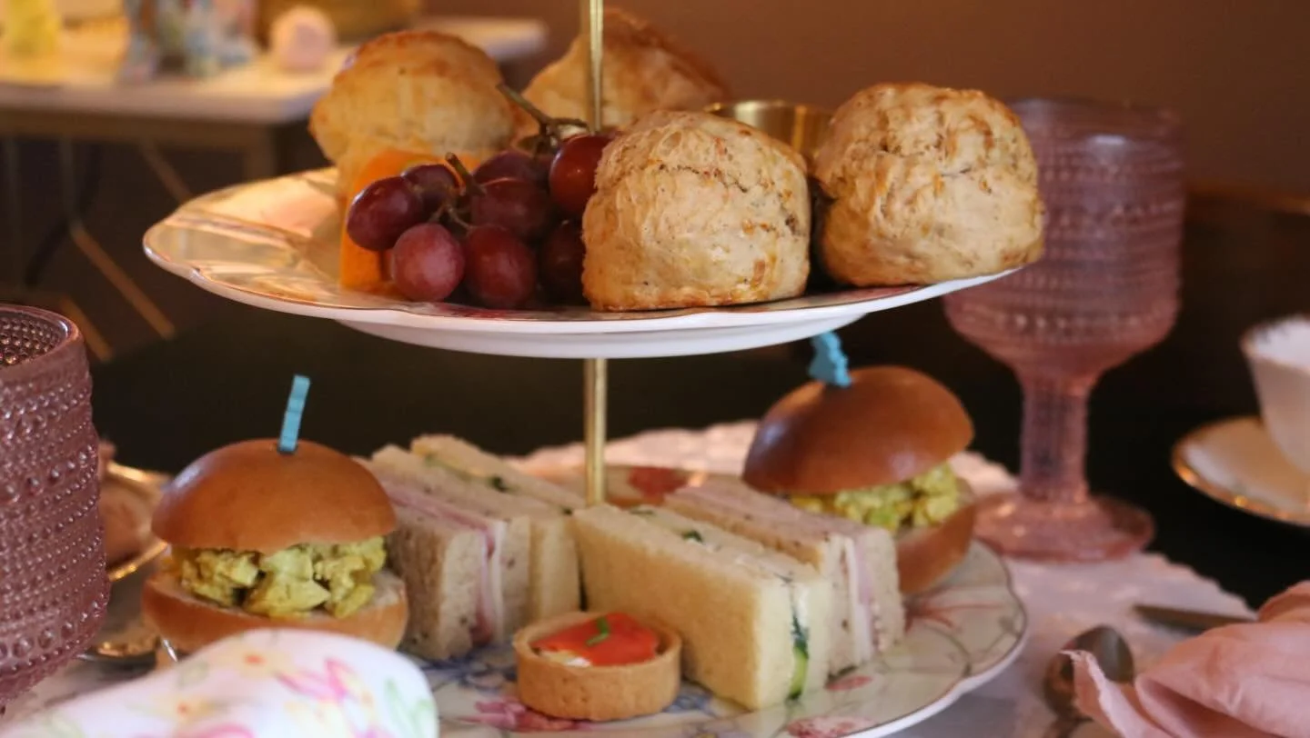 Three-tiered dessert stand with baked goods, macarons, and chocolates at a celebration.