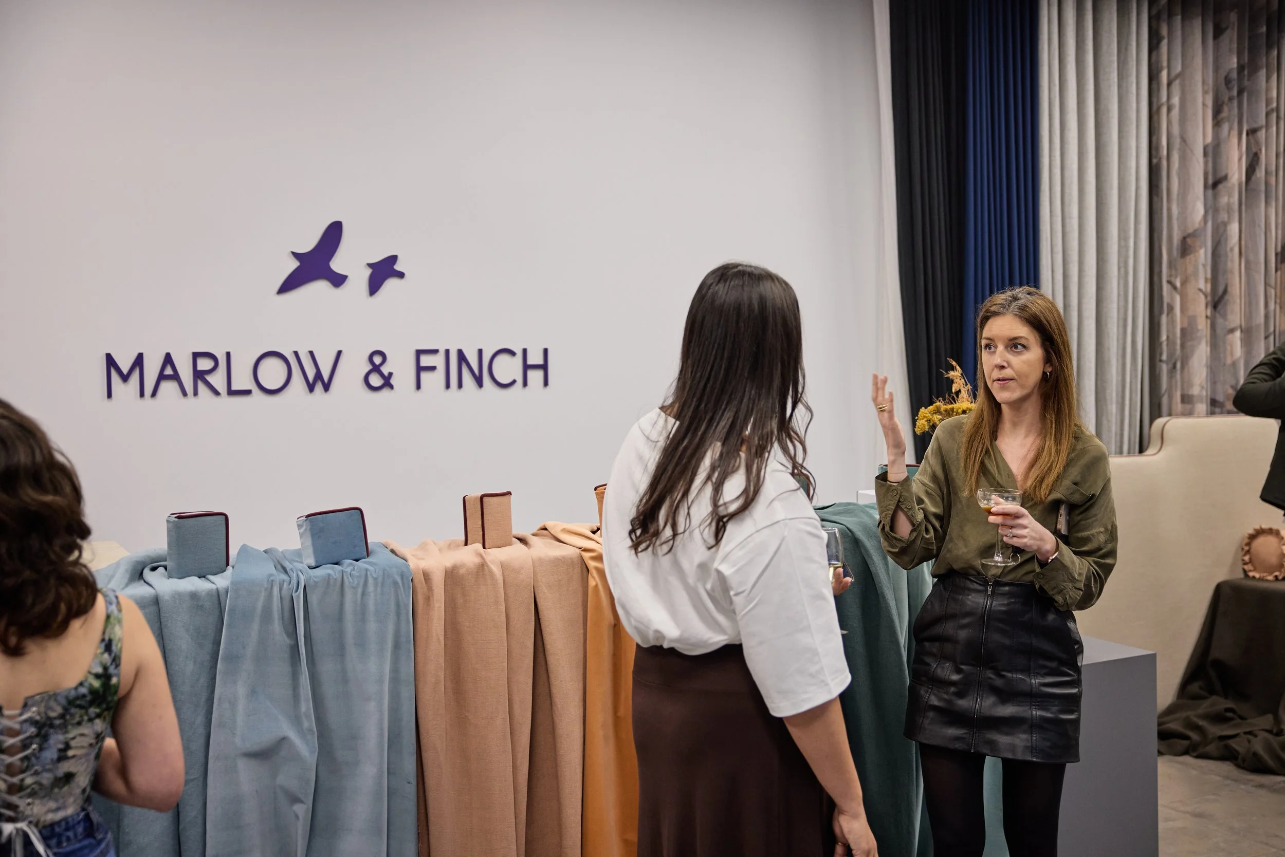 Women socializing at an event with a Marlow & Finch display and logo on the wall.