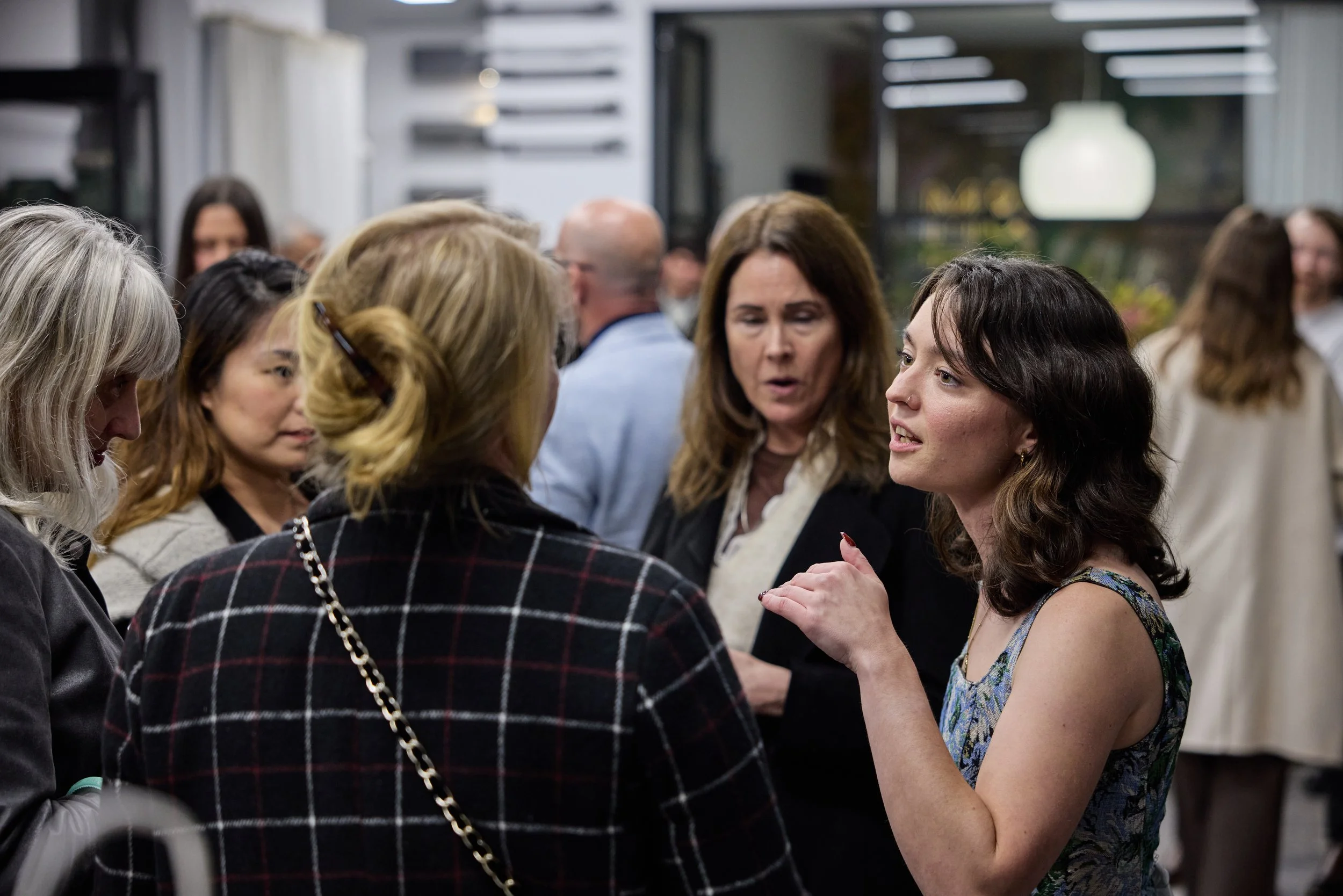 Group of women engaging in conversation at an indoor social event.