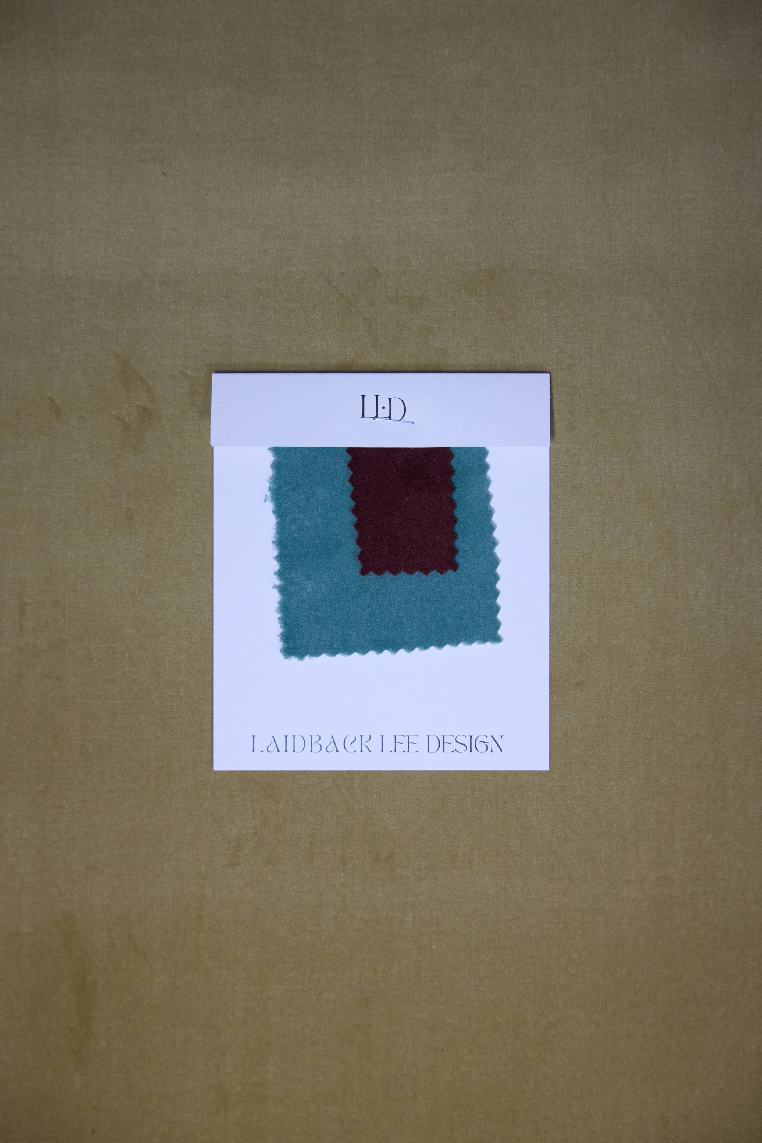 Color swatch fabric sample with teal and maroon colors on a white paper with text reading 'L.L.D' and 'Laidback Lee Design'.