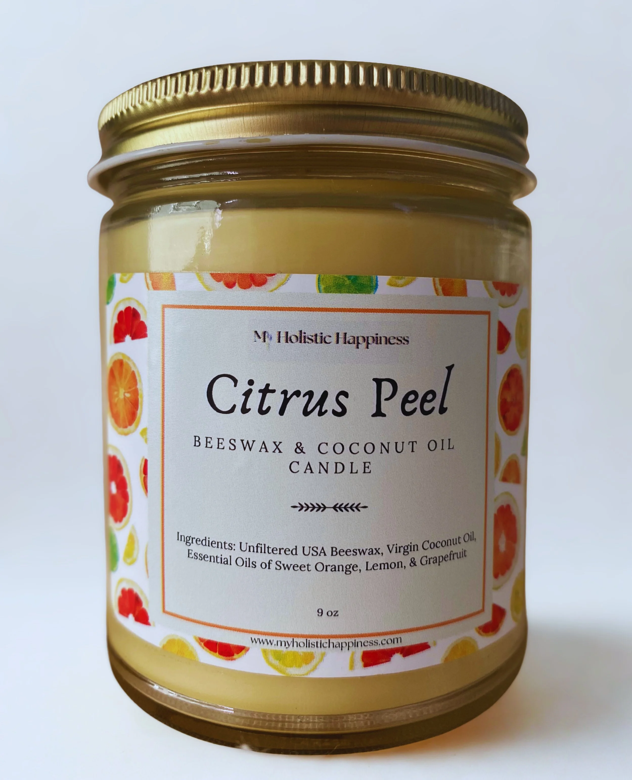 A glass jar labeled citrus peel natural essential oil beeswax candle by My Holistic Happiness flaunts a label with lemons, oranges, and limes.