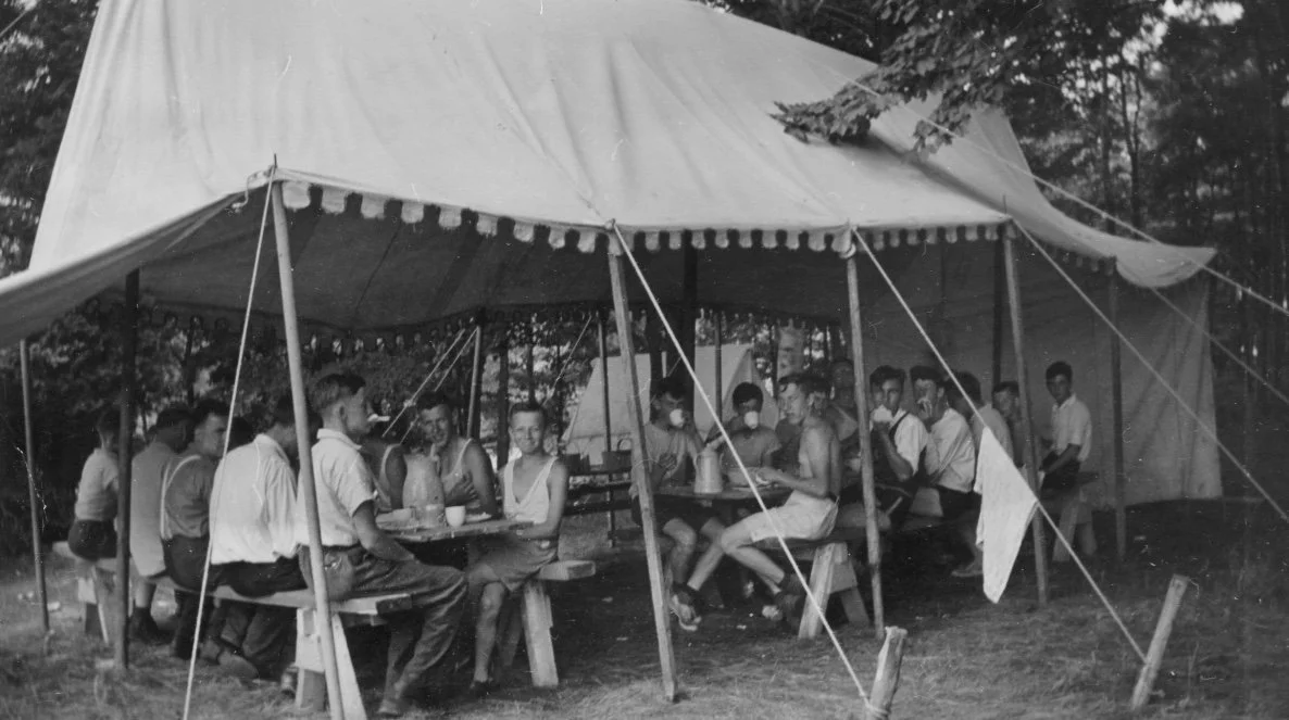 This photo shows the dining area at the very first camp session. It was a boys' camp and they used a marquis with nailed together tables and benches for seating.  It was definitely a used marquis because it was missing a good number of panels so not 