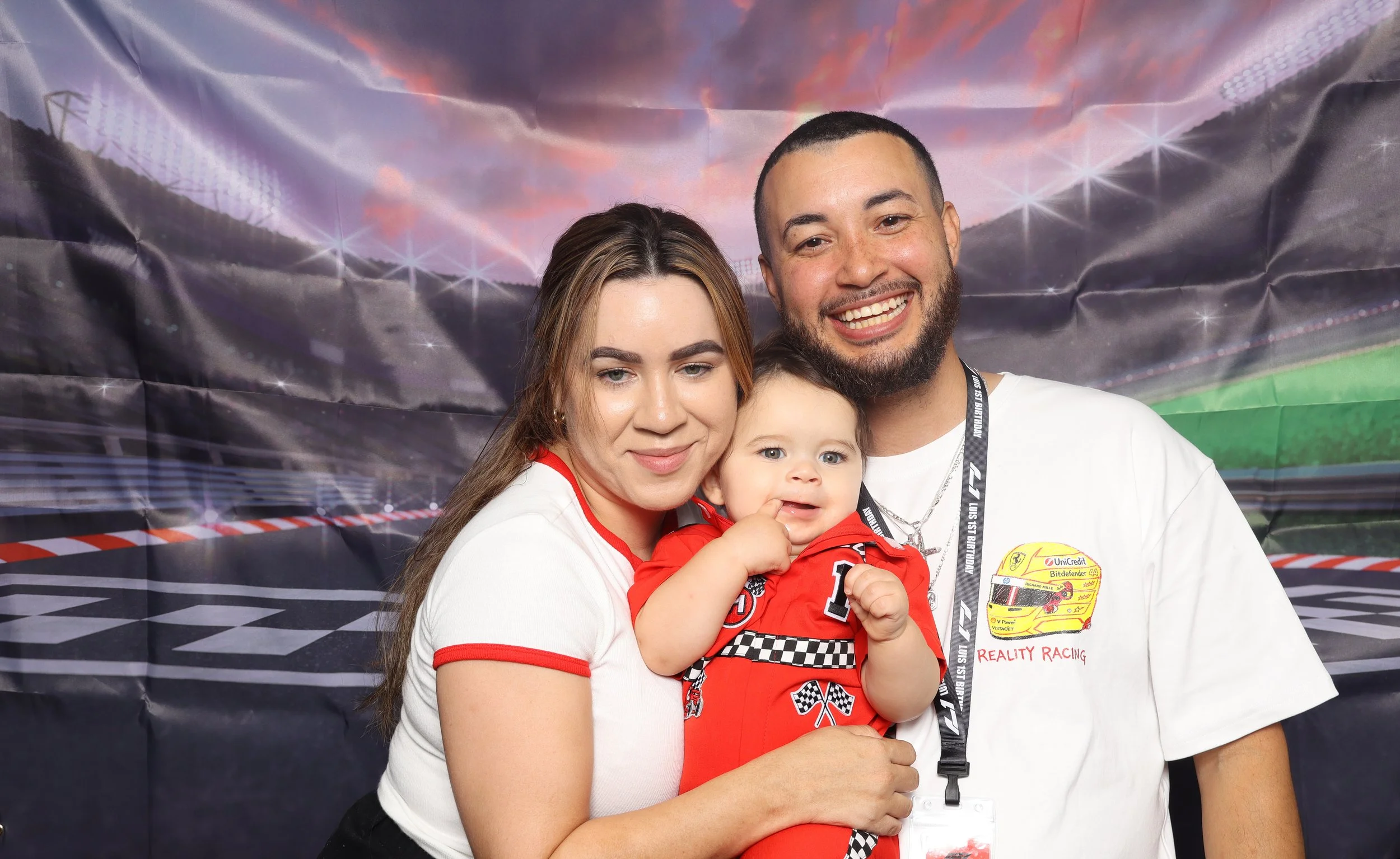 Family with a baby posing at a photo booth with a sports stadium backdrop at photo booth rental in Orlando, FL — D&amp;L Photobooths