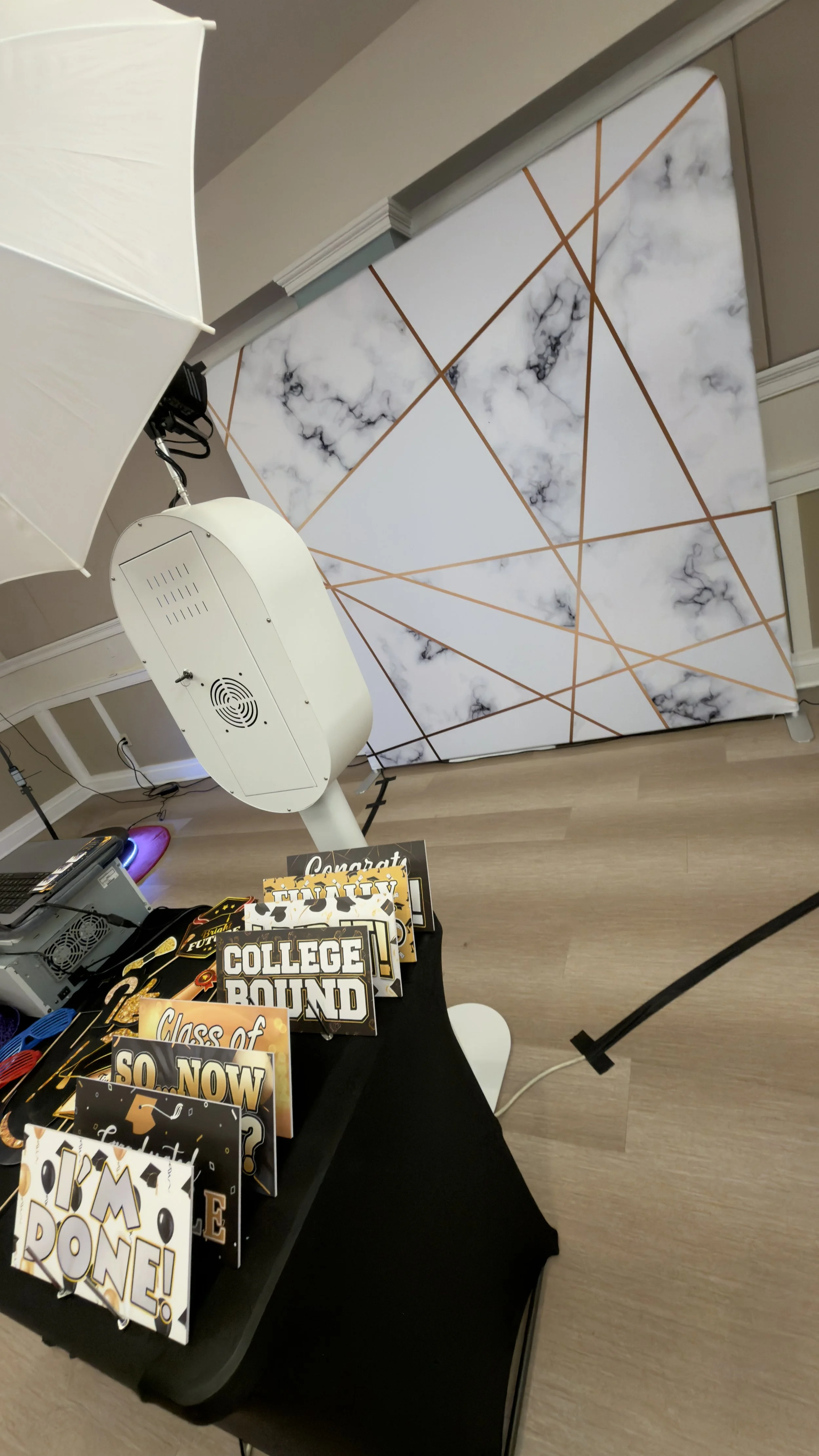 Photo booth setup with white marble and gold backdrop and graduation party props at an event in South Florida