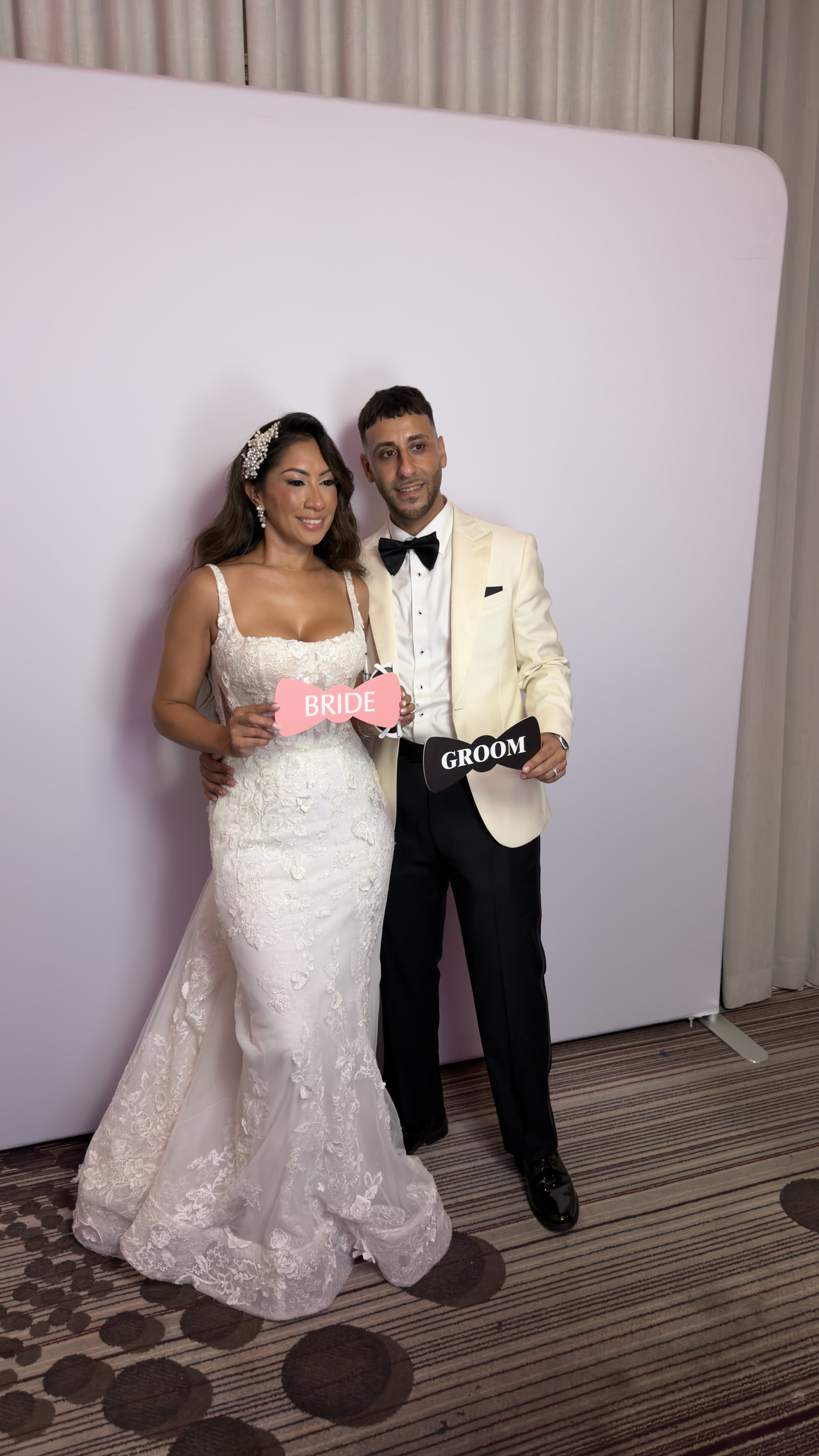 Bride and groom in white wedding attire posing together at a D&L Photobooths photo booth in Florida