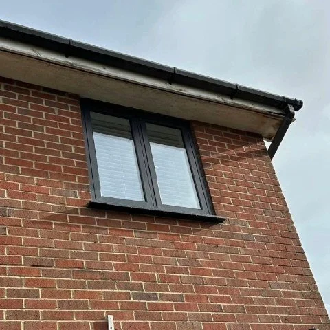 Image showing the rear of a detached property in Poole before its roofline is replaced with new anthracite grey UPVC fascias and soffits and black half round guttering