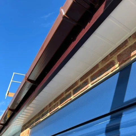 Image shows the close up of new Rosewood UPVC fascias, white UPVC tongue and groove soffits and brown square UPVC guttering in Poole