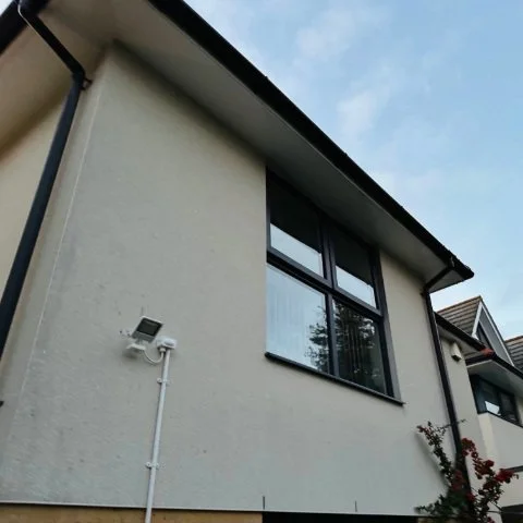 Image shows new black UPVC guttering and black UPVC downpipe replacement on the rear of a detached property in Poole, Dorset after guttering repair