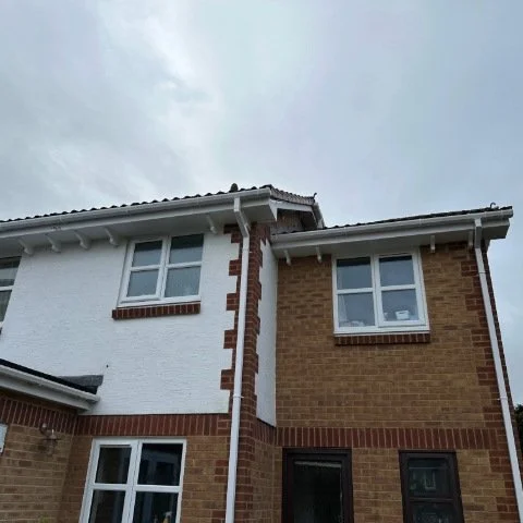 Image showing front of detached property in Broadstone, Poole with new white UPVC Fascias, white UPVC tongue and grove Soffits and white square UPVC guttering and white square downpipe