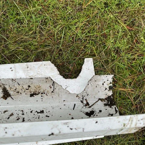 a piece of gutter and fascia removed from the property to show the damage caused by a squirrel