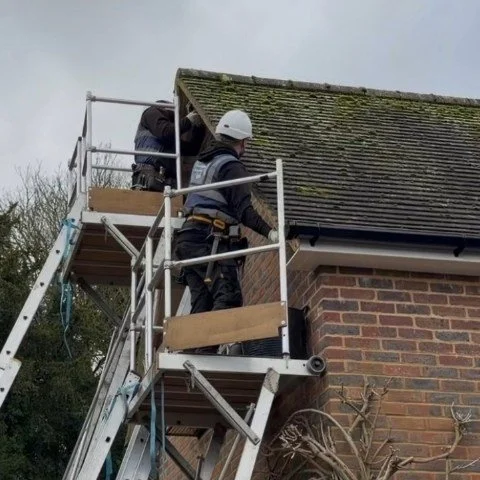 Image shows access equipment on detached property in Wimborne Dorset to instal white UPVC fascias, white UPVC soffits and white UPVC bargeboards and new black square UPVC guttering and downpipes