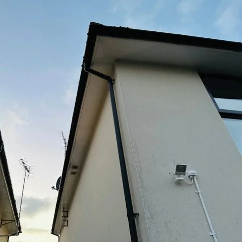 Image shows new black UPVC guttering and black UPVC downpipe replacement on the side and rear of a detached property in Poole, Dorset after guttering repair