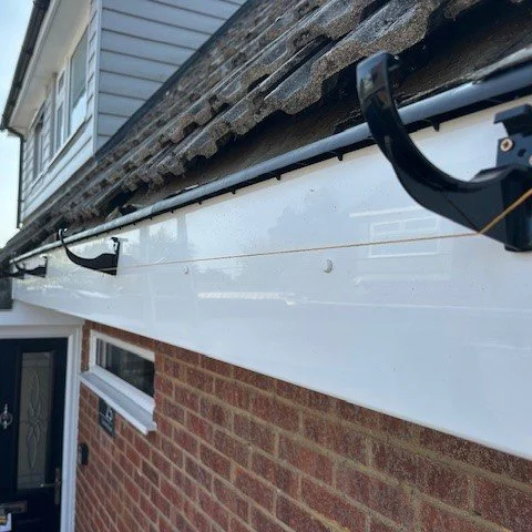 image showing new black round guttering being fitted with the aid of a stringline 