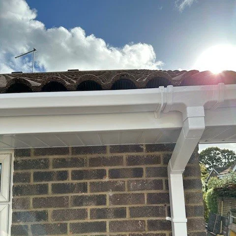 close up showing white square guttering and white fascias with the sun in the background
