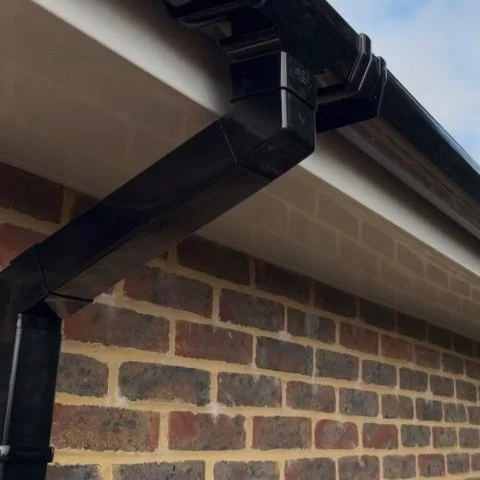 Image shows close up of replacement white UPVC fascias, white UPVC soffits and new black square UPVC guttering and downpipes in Wimborne Dorset