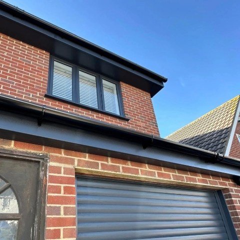 Image showing the front of a detached property in Poole with new anthracite grey UPVC fascias and soffits and black half round guttering