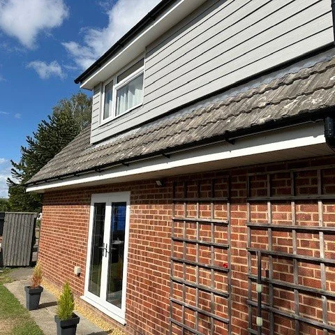 side view of the bungalow with newly fitted white fascias and soffits with black round guttering and cladding on the dorma above