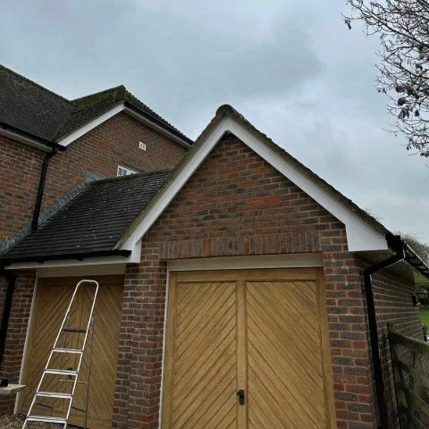 image shows garage on detached property in Wimborne Dorset with replacement white UPVC fascias, white UPVC soffits and white UPVC bargeboards and new black square UPVC guttering and downpipes