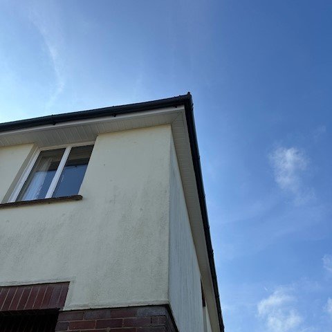front right corner of a detached property showing black half round guttering and white fascias and soffits