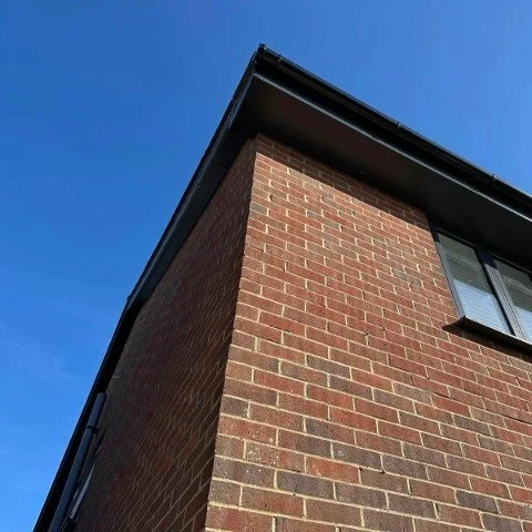 Image showing the rear and side of a detached property in Poole with new anthracite grey UPVC fascias and soffits, anthracite grey UPVC bargeboards and black UPVC half round guttering
